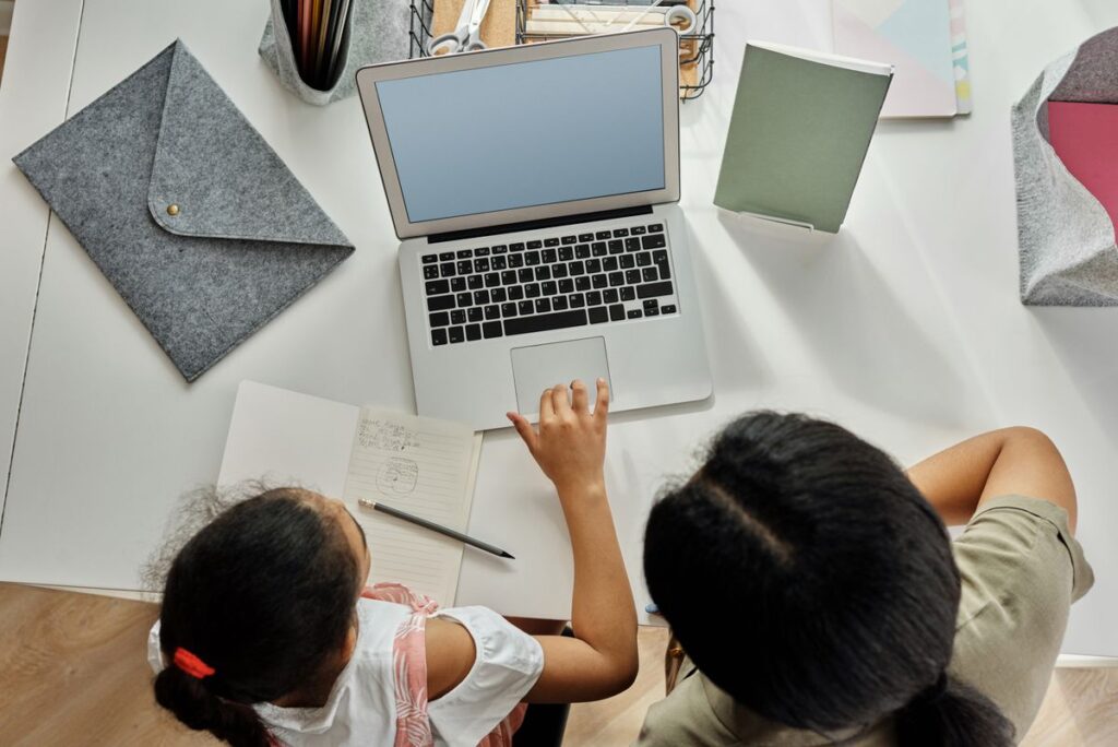 Madre ayudando a su hija con tareas en laptop