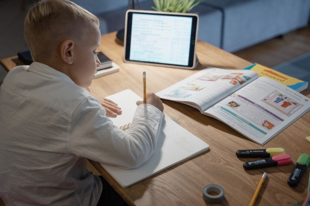 Niño haciendo tarea con cuaderno y tablet